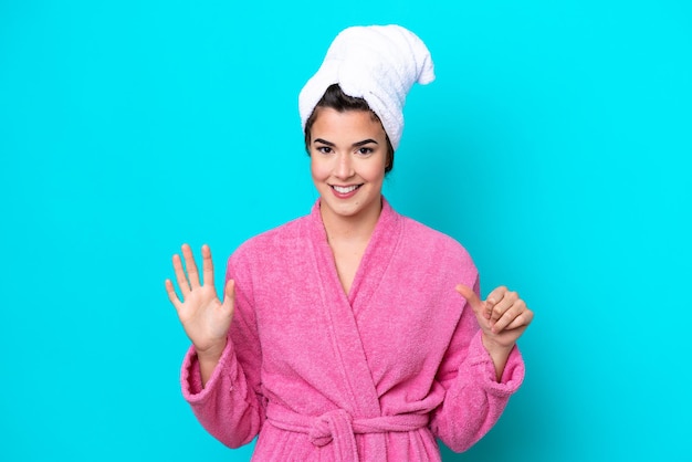 Young Brazilian woman with a bathrobe isolated on blue background counting six with fingers