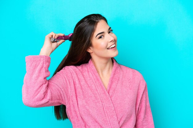 Young brazilian woman with hair comb isolated on blue background