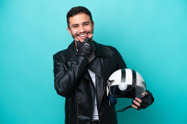 Молодая бразильянка в мотоциклетном шлеме на синем фоне счастлива и улыбается