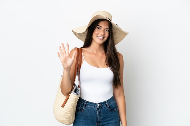 Young Brazilian woman with Pamela holding a beach bag isolated on white background counting five with fingers