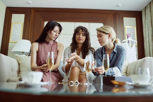 Young bride to be looking at pearl bracelet on her wrist between two friends