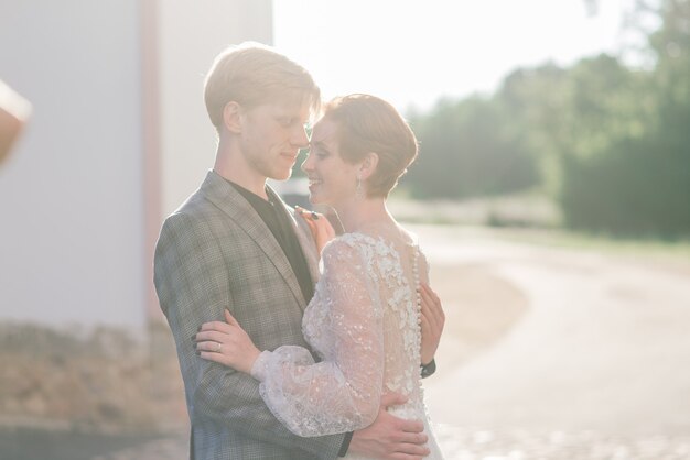 若い新郎新婦のカップルはお互いを抱きしめて入札します。夏の結婚式、赤毛の女性と男性。