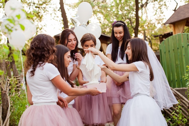 Young bride opens the gift box at girls party Beautiful women friends in dress code having fun together