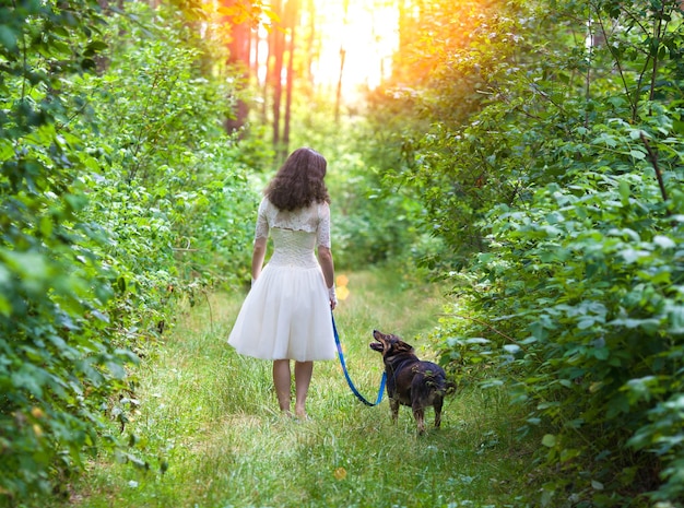 Giovane sposa che cammina con il cane sulla strada rurale