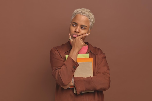 Photo young brooding african american woman student with workbooks stands in studio