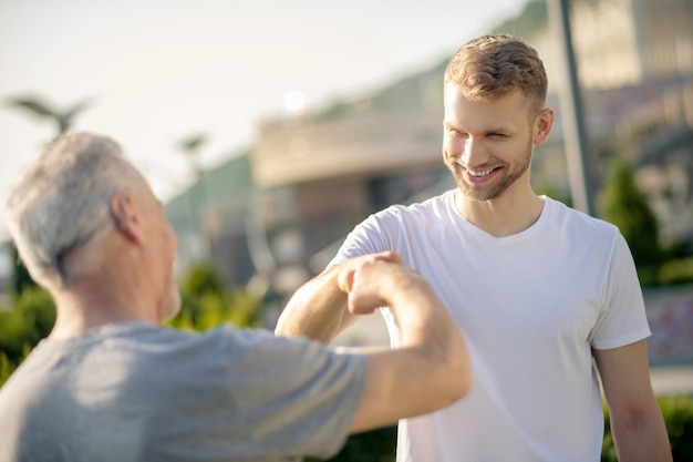 拳に触れる若い茶色の髪の男性と白髪の男性