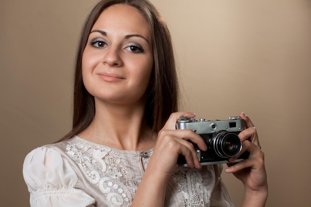 Young brown haired woman in beautiful dress holding retro camera