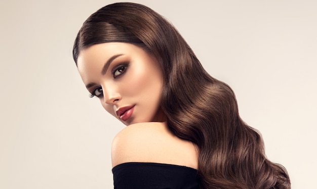 Young brown haired woman with long elegant wavy hairstyle Glance back over shoulder Hairdressing art