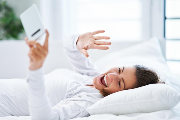 Young brunet woman with smartphone on the bed