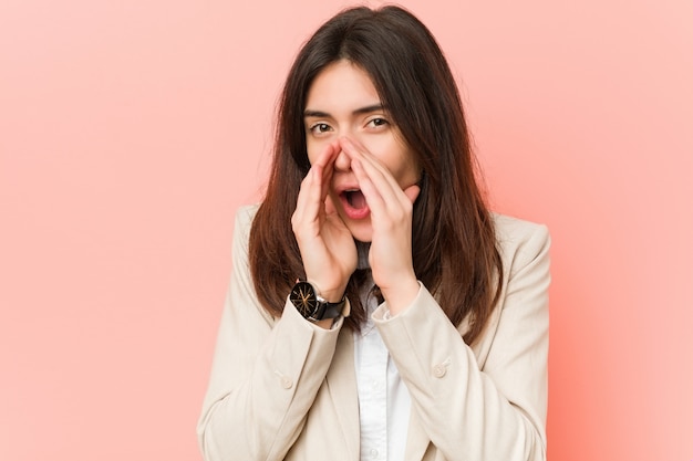 Young brunette business woman againstpink  shouting excitedfront.