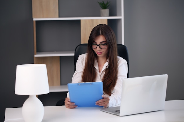 Young brunette business woman with laptop in the office.