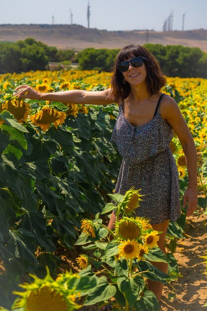 A young brunette Caucasian enjoying some beautiful sunflowers