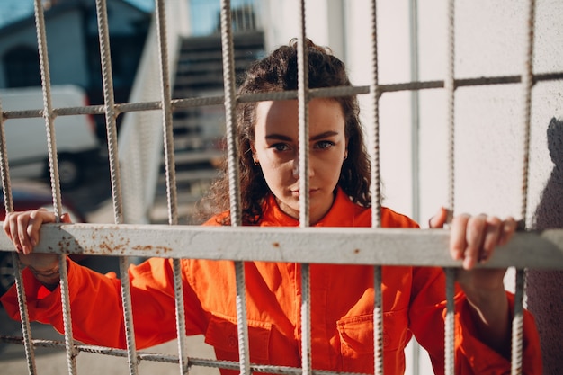 Photo young brunette curly woman in orange suit. female in colorful overalls portrait.