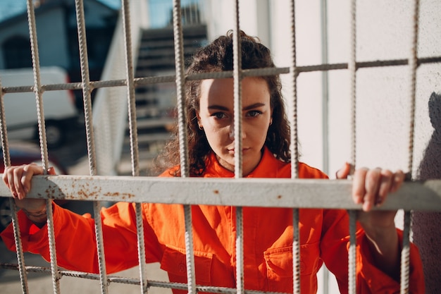 Young brunette curly woman in orange suit. Female in colorful overalls portrait.