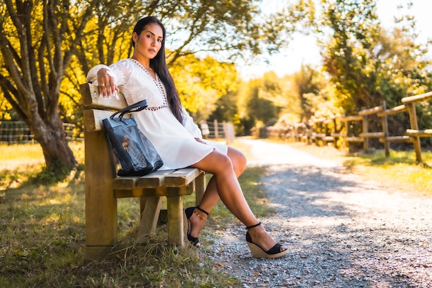 Foto giovane bruna che gode di un parco in un vestito bianco