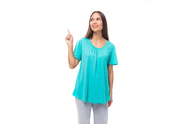 Young brunette european lady with straight hair dressed in a blue tshirt demonstrates with a hand