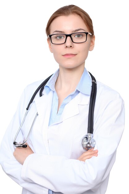 腕を組んで立っている若いブルネットの女医師。白い背景の上に分離。