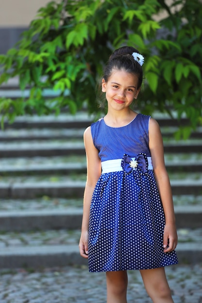 Young brunette girl in a blue dress in the park in the summer. High quality photo