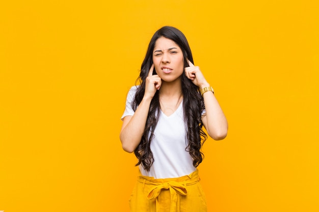 young brunette girl covering both ears to a deafening noise