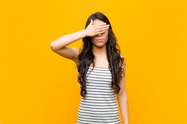 young brunette girl covering eyes with one hand