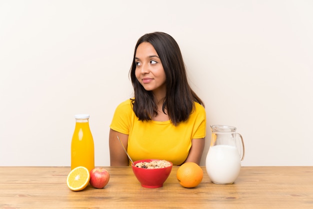 Young brunette girl having breakfast milk standing and looking to the side