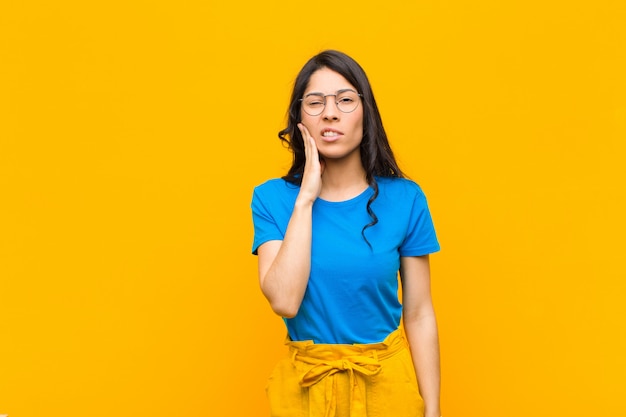 young brunette girl holding cheek and suffering painful toothache