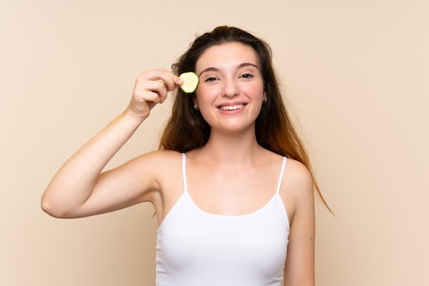 Young brunette girl holding slices of cucumber 