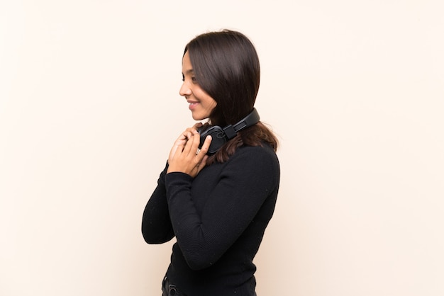 Young brunette girl listening music over isolated wall