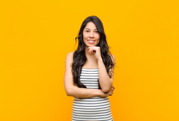 young brunette girl looking happy and smiling with hand on chin