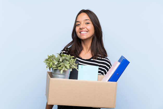 Young brunette girl making a move while picking up a box full of things smiling a lot