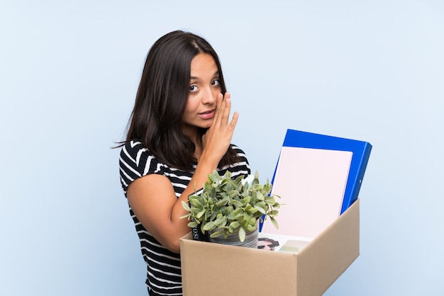 Young brunette girl making a move while picking up a box full of things whispering something