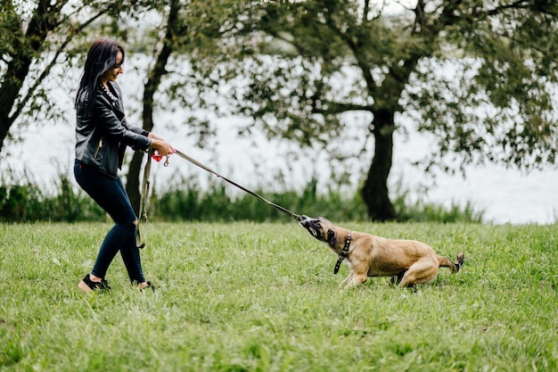Фото Молодая брюнетка девушка играет с забавной собакой на природе