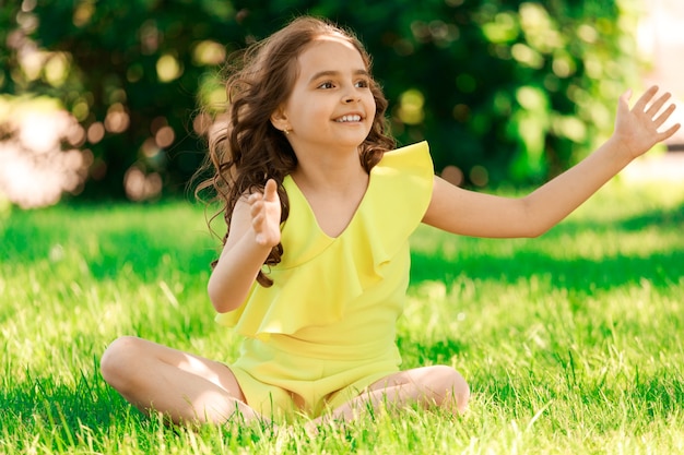 Young brunette girl sitting on the grass in the park. High quality photo