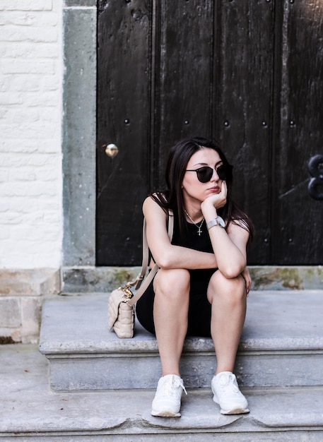 Young brunette girl sitting on the porch near the house