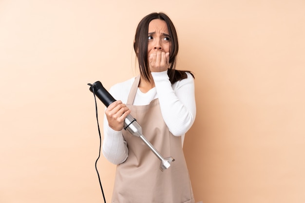 Young brunette girl using hand blender isolated