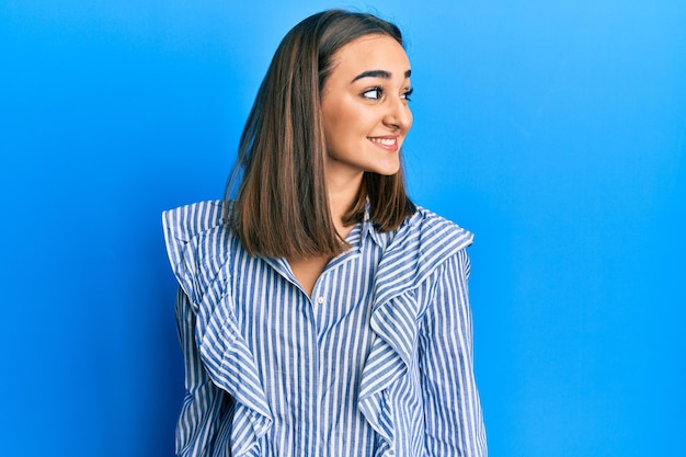 Young brunette girl wearing casual blue shirt looking to side, relax profile pose with natural face and confident smile.