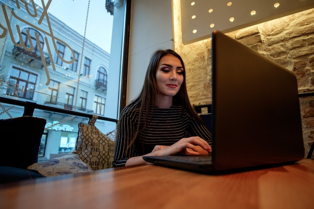 Young brunette girl with laptop in cafe