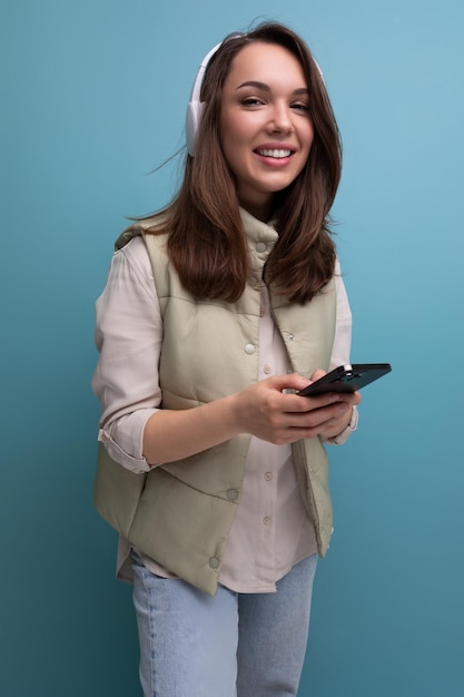 若いブルネットの女性は、ヘッドフォンを使用して携帯電話のビデオ通話で通信します