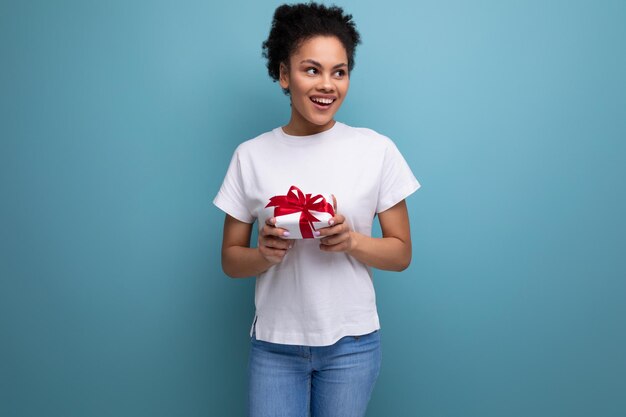 Young brunette latin woman in white tshirt is happy to hold received gift in her hands