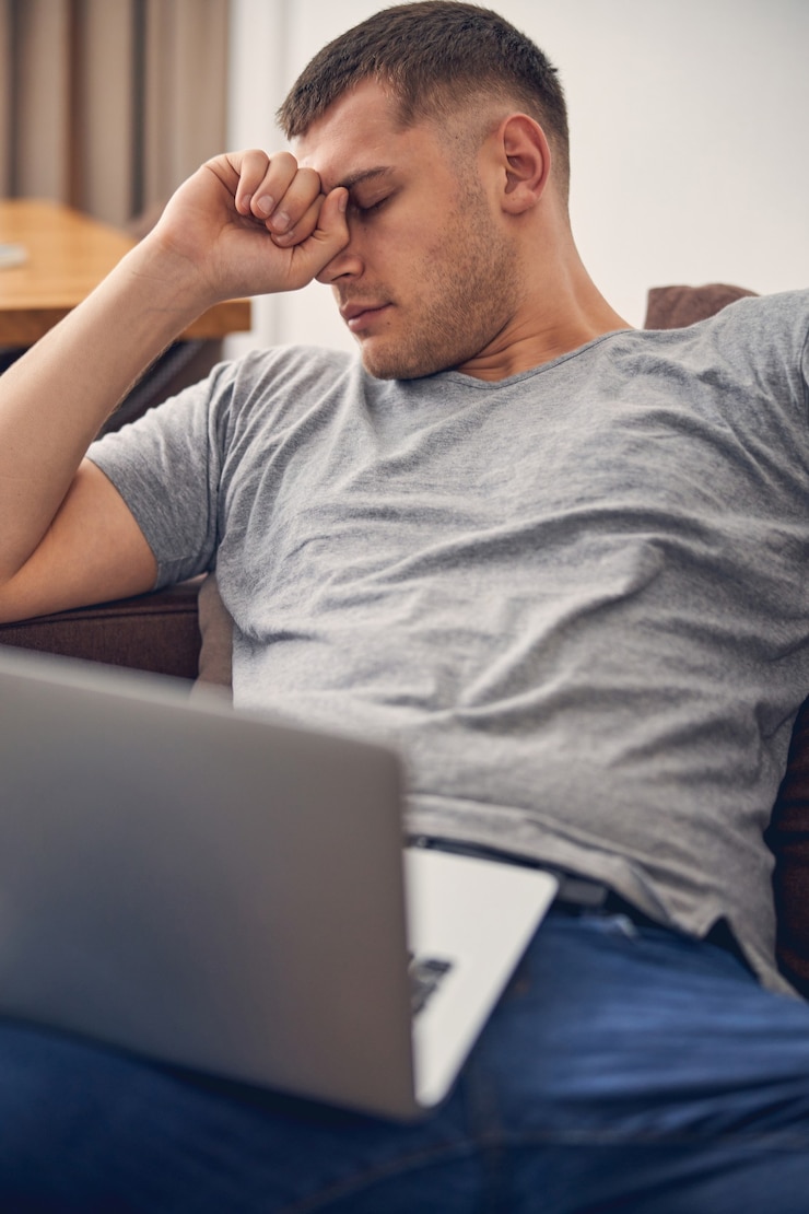 Photo young brunette male sleeping on sofa while holding laptop on his knees