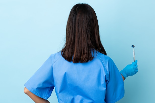 Photo young brunette mixed race dentist woman holding tools over in back position