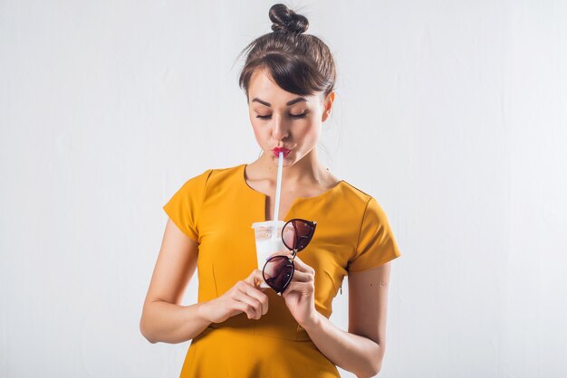 Young brunette model posing drinking cocktail studio shot on white background, not isolated