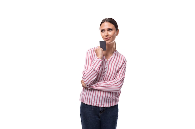 Молодая брюнетка, работающая в офисе, женщина в рубашке, держащая кредитную карту с макетом