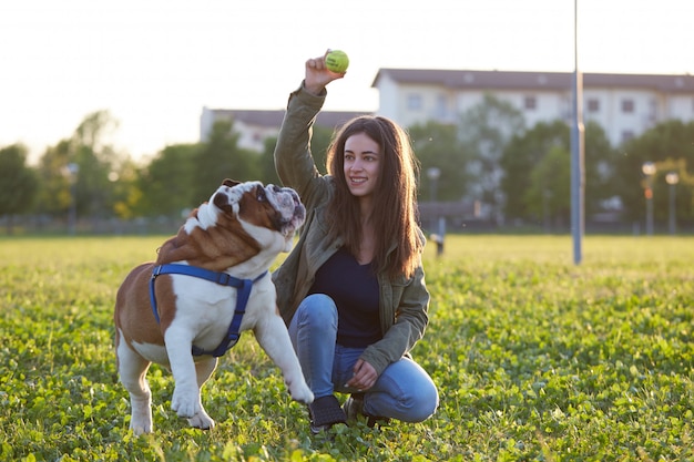 Photo young brunette play with her british bulldog