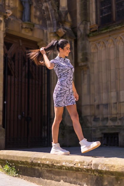 Young brunette posing in a church doorway in summer wearing a zebra print jumpsuit