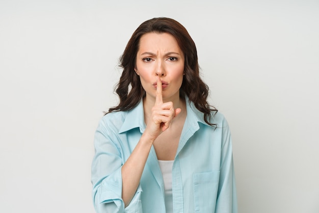 Young brunette shows the silence gesture