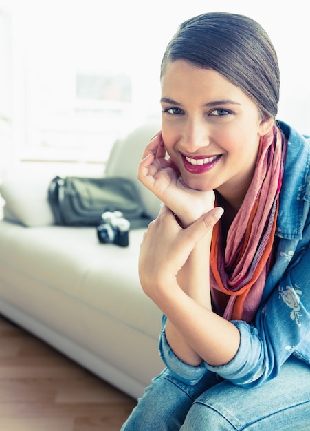 Young brunette sitting on sofa looking at camera