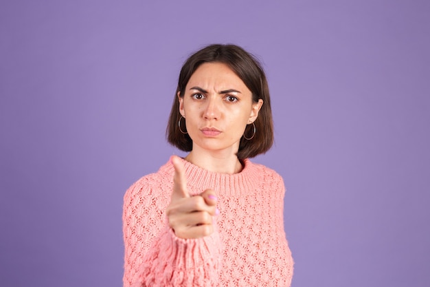 Young brunette in sweater isolated on purple wall