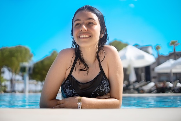 Молодая брюнетка-подросток позирует в голубом бассейне в отеле в Турции