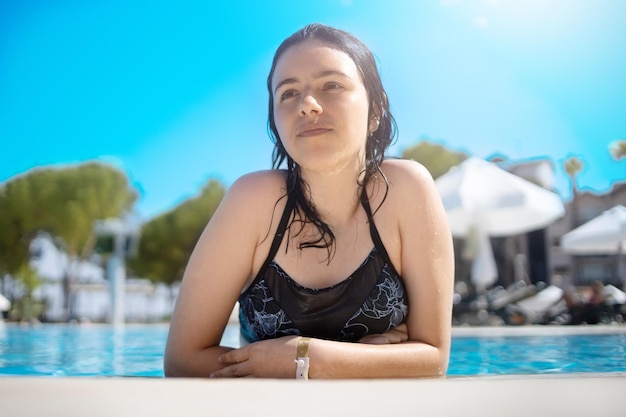 Giovane ragazza adolescente bruna in posa in una piscina blu in un hotel in turchia